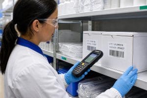 Profissional confere com coletor móvel caixas do mesmo produto identificadas por lotes e validades diferentes.