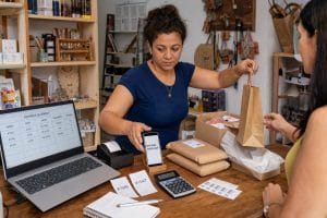 Microempreendedora divide a atenção entre novos pedidos, atendimento e atualização manual de uma planilha.